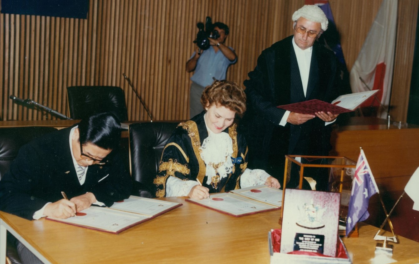 Mayor of Ube, Mr Hideo Futatsugi, and Newcastle Lord Mayor Joy Cummings sign the declaration while Town Clerk Barrie Lewis looks on.jpg
