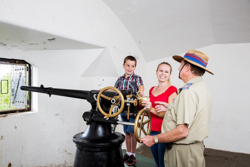 Mother and son on a tour of Fort Scratchley being shown a historic gun by a guide from the Fort Scratchley Historical Society